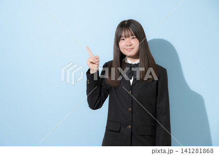 水色背景で制服で立つカメラ目線笑顔の女子中学生や高校生のイメージ 指差しでポイントのポーズで大笑い 水色背景で制服で立つカメラ目線笑顔の女子中学生や高校生のイメージ 指差しでポイントのポーズで大笑い 141281868