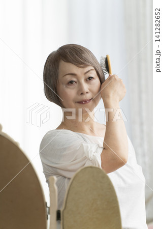 ブラシでヘアスタイルを整えるシニア女性 141282652