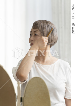 ブラシでヘアスタイルを整えるシニア女性 141282682