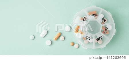 Vitamins and supplements with daily pill box on light green background, top view 141282696