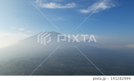Misty mountain peaks rise above lush green forests Misty mountain peaks rise above lush green forests 141282994