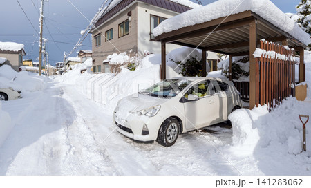 大雪の翌朝、雪かきをしてやっと駐車場から車を出す 141283062