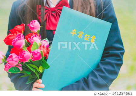 制服の女子高生が卒業証書と花束を胸に抱えて立つ 制服の女子高生が卒業証書と花束を胸に抱えて立つ 141284562