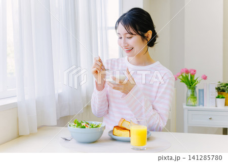 朝食でヨーグルトを食べる若い女性 朝食でヨーグルトを食べる若い女性 141285780