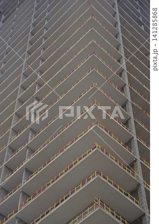 Modern concrete skyscraper under construction with yellow safety barriers and copy space Modern concrete skyscraper under construction with yellow safety barriers and copy space 141285868