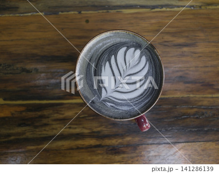Hot latte in red cup on wooden table 141286139