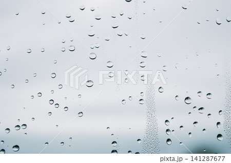 raindrops during raining in the rainy day outside window glass with a blurred background with water droplets flowing down the surface raindrops during raining in the rainy day outside window glass with a blurred background with water droplets flowing down the surface 141287677