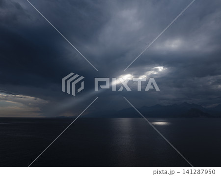 Dramatic light beams between clouds above ocean Dramatic light beams between clouds above ocean 141287950