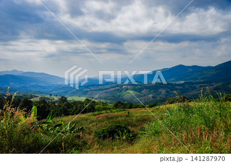 Mountains hills with many agriculture fields surrounded by nature with cloudy sky Mountains hills with many agriculture fields surrounded by nature with cloudy sky 141287970