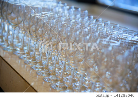 Many empty wine glasses line up waiting to pour some liquor for many invitation guests in the dinner reception celebration party in a lounge in the hotel. Many empty wine glasses line up waiting to pour some liquor for many invitation guests in the dinner reception celebration party in a lounge in the hotel. 141288040