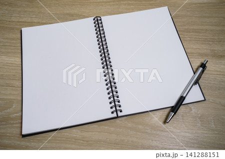 an opened blank page of a notebook with a pen on the table an opened blank page of a notebook with a pen on the table 141288151