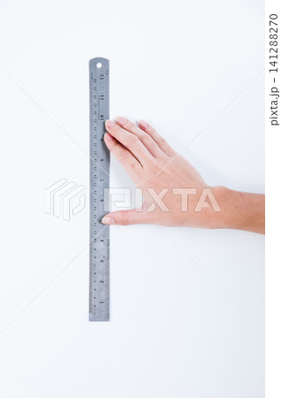 a hand of a man holding a ruler to measure something in white background a hand of a man holding a ruler to measure something in white background 141288270