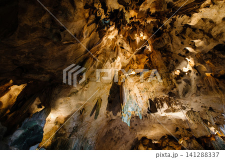 a cave with stalagmites and stalactites. The cave is large and dark, and the walls are covered in a variety of different rock formations. The stalagmites and stalactites are a variety of shapes and a cave with stalagmites and stalactites. The cave is large and dark, and the walls are covered in a variety of different rock formations. The stalagmites and stalactites are a variety of shapes and 141288337