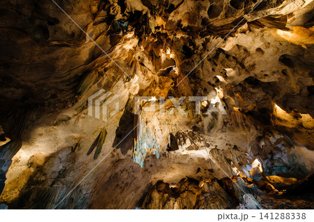 a cave with stalagmites and stalactites. The cave is large and dark, and the walls are covered in a variety of different rock formations. The stalagmites and stalactites are a variety of shapes and a cave with stalagmites and stalactites. The cave is large and dark, and the walls are covered in a variety of different rock formations. The stalagmites and stalactites are a variety of shapes and 141288338