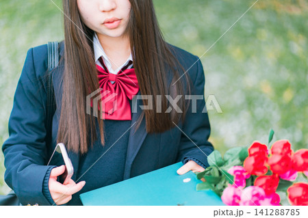 卒業証書と花束とスマホを持つ女子高生 141288785