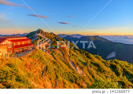 初秋の早朝 燕岳の燕山荘付近から望むモルゲンロートのピンクに染まる燕山荘と燕岳の風景 141288877