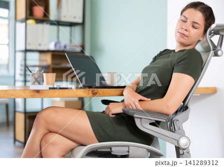 Young woman in dress sleeping sitting at office desk 141289312