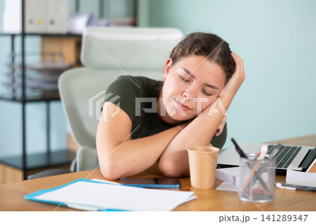 Young woman in dress sleeping sitting at office desk Young woman in dress sleeping sitting at office desk 141289347