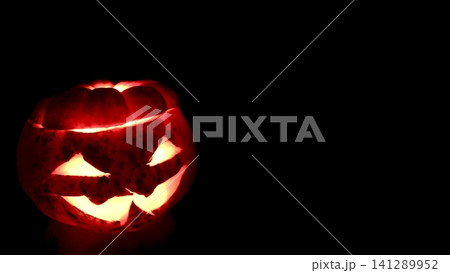 暗闇に妖しく光るジャックオーランタンのハロウィン横長バナー素材(左配置・右コピースペース) 暗闇に妖しく光るジャックオーランタンのハロウィン横長バナー素材(左配置・右コピースペース) 141289952