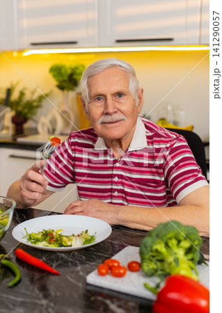 Senior old man happily eating fresh vegetable salad in home kitchen for healthy diet and weight loss Senior old man happily eating fresh vegetable salad in home kitchen for healthy diet and weight loss 141290057