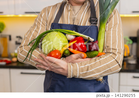 Unrecognizable man holding fresh vegetables in kitchen for diet meal healthy nutrition and home food Unrecognizable man holding fresh vegetables in kitchen for diet meal healthy nutrition and home food 141290255
