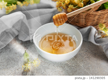 Linden honey dripping from dipper in white bowl Linden honey dripping from dipper in white bowl 141290305