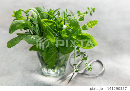 Fresh herbs bouquet in glass with scissors 141290327