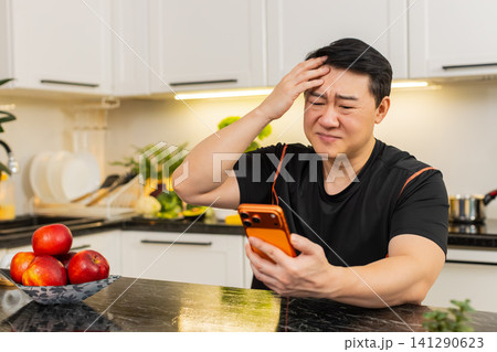 Upset Asian man reacts to game result on orange smartphone after losing lottery in online casino app Upset Asian man reacts to game result on orange smartphone after losing lottery in online casino app 141290623