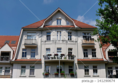 Symmetrical facade of a classic European apartment building with red roof Symmetrical facade of a classic European apartment building with red roof 141290674