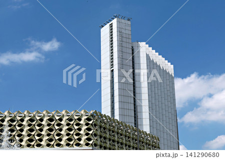 Tall white modernist skyscraper building against a bright blue sky with clouds Tall white modernist skyscraper building against a bright blue sky with clouds 141290680