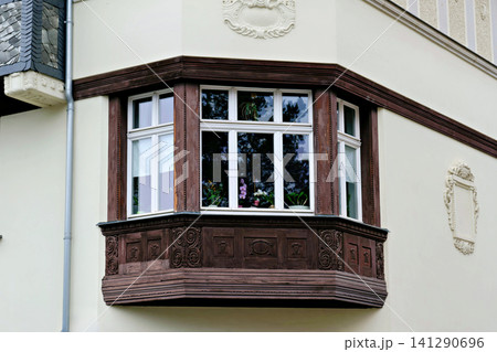 Vintage wooden bay window with blooming orchids inside on historical building facade Vintage wooden bay window with blooming orchids inside on historical building facade 141290696