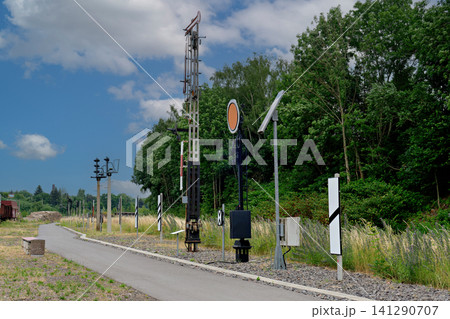 Vintage mechanical railway signals and poles along path next to forest Vintage mechanical railway signals and poles along path next to forest 141290707