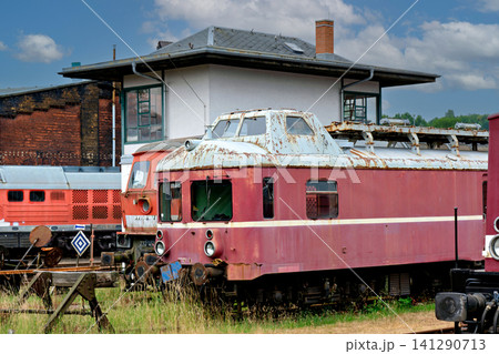 Old abandoned rusty pink railcar parked near an old railway station building 141290713