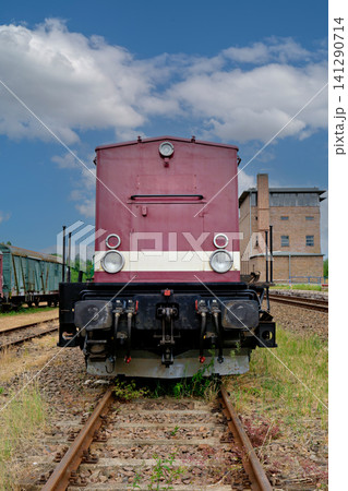 Front view of a vintage maroon diesel locomotive on railway tracks under blue sky Front view of a vintage maroon diesel locomotive on railway tracks under blue sky 141290714