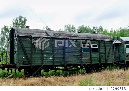 Vintage dark green wooden freight train wagon with peeling paint parked on dry grass field Vintage dark green wooden freight train wagon with peeling paint parked on dry grass field 141290718