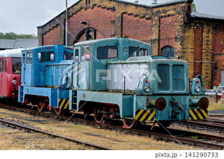 Historic blue industrial shunting locomotives on tracks next to a classic brick roundhouse Historic blue industrial shunting locomotives on tracks next to a classic brick roundhouse 141290733