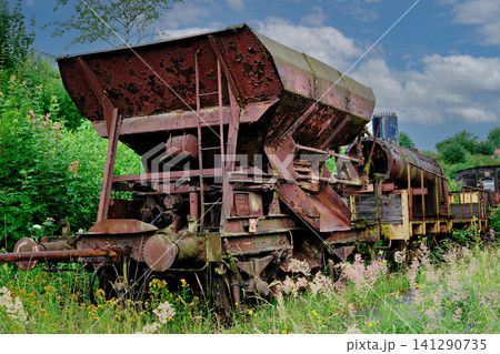 Old rusty metal freight hopper car abandoned on railroad track among grass Old rusty metal freight hopper car abandoned on railroad track among grass 141290735