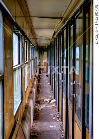 Narrow messy corridor inside a decaying abandoned passenger train wagon with glass doors Narrow messy corridor inside a decaying abandoned passenger train wagon with glass doors 141290738
