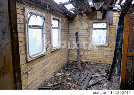 Destroyed interior of an old train car with yellow walls and a collapsed ceiling Destroyed interior of an old train car with yellow walls and a collapsed ceiling 141290744