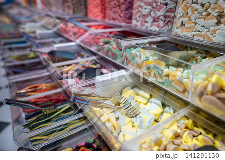 showcase of candy shop, transparent container with various sweets, marshmallow, jelly, chewy gums, rich sugar assortment 141291130