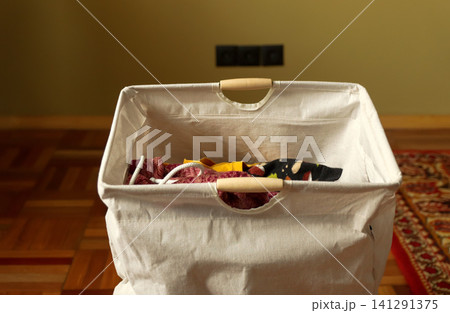 Laundry basket with colorful clothes inside, concept of household chores, organization and clean home living. An empty laundry basket ready for sorting clothes, symbolizing home organization Laundry basket with colorful clothes inside, concept of household chores, organization and clean home living. An empty laundry basket ready for sorting clothes, symbolizing home organization 141291375