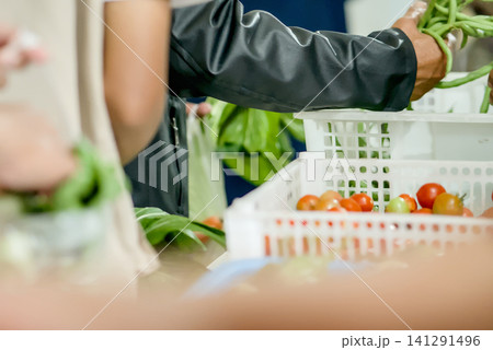 resh vegetables for sale at a local market stall, featuring carrots in a white plastic crate and leafy greens in the background	 141291496