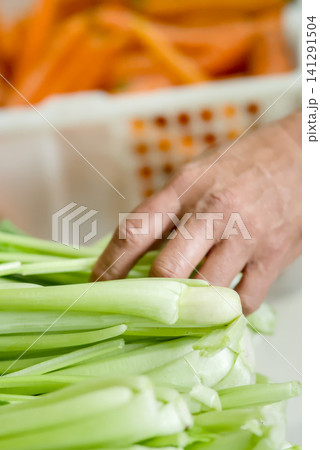 resh vegetables for sale at a local market stall, featuring carrots in a white plastic crate and leafy greens in the background	 141291504