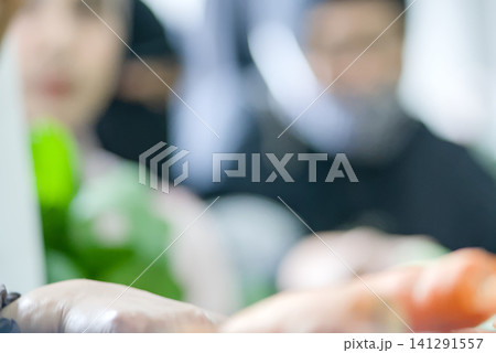 Closeup of hands holding fresh green leafy vegetables and small red tomatoes during a food distribution or market activity Closeup of hands holding fresh green leafy vegetables and small red tomatoes during a food distribution or market activity 141291557