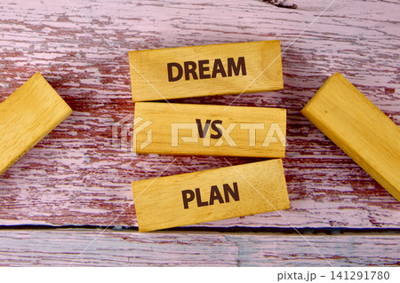 Wood blocks are arranged on a pink wooden surface with the words dream and plan. This shows a comparison between ideas and actions 141291780