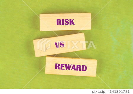Three wooden blocks display the words risk, vs, and reward in a discussion about decision making. This scene is set on a flat surface during a workshop 141291781