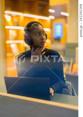 Student wearing headphones studying on laptop Student wearing headphones studying on laptop 141292169