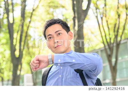 ビジネスマン、木漏れ日の中で時計を確認する ビジネスマン、木漏れ日の中で時計を確認する 141292416