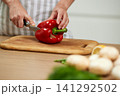 Person cutting red bell pepper on cutting board 141292502