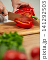 Hands cutting red bell pepper on wooden board 141292503